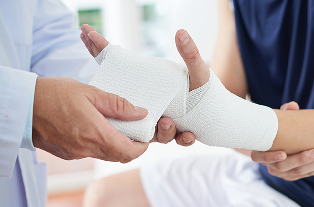 Un médecin enveloppe le poignet d'une personne dans de la gaze pour traiter une blessure au poignet.