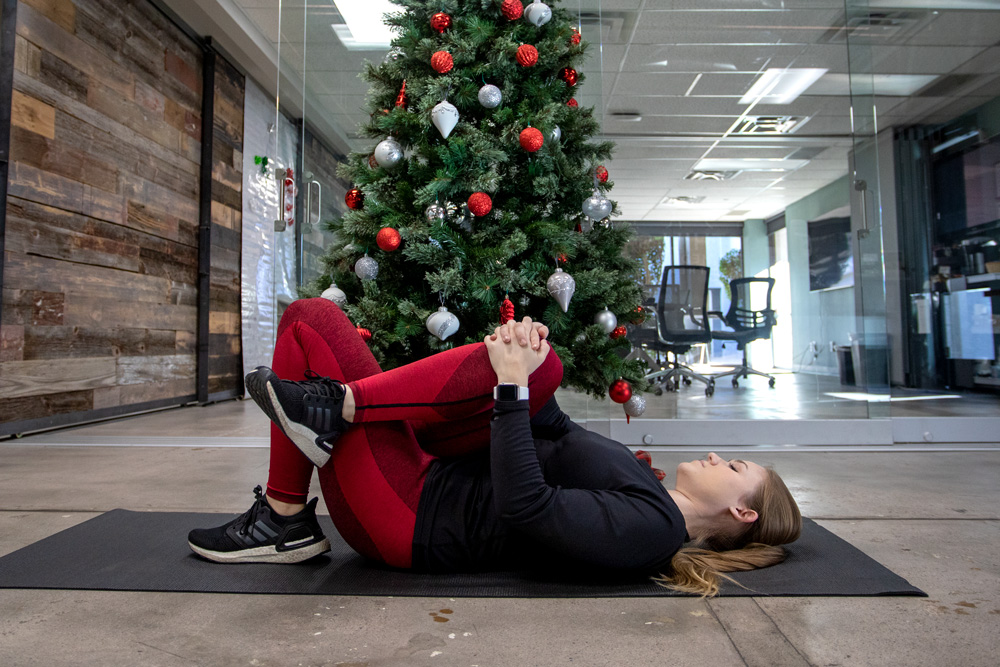 Femme qui s'étend de la jambe devant l'arbre de Noël