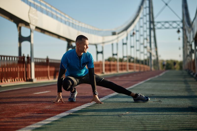 Athlète d'âge moyen faisant des exercices d'échauffement avant de commencer à courir