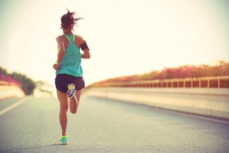 Coureur de jeune femme courant sur la route du pont de la ville