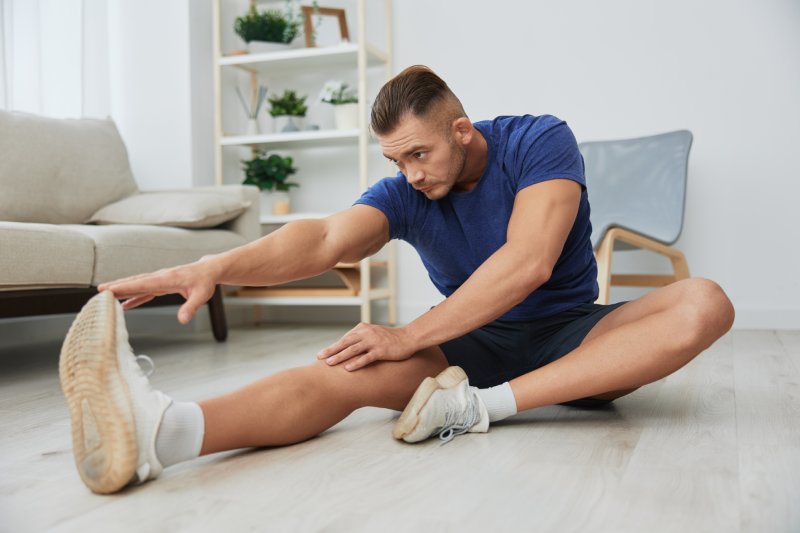 Homme sportif s'entraînant à la maison, exercices d'étirement pour les muscles des bras, des jambes et du dos, corps fort et posture correcte, le concept de santé et de beauté