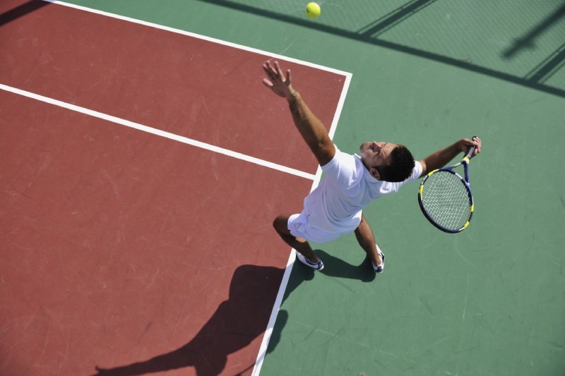 jeune homme joue au tennis en plein air sur un terrain de tennis orange tôt le matin