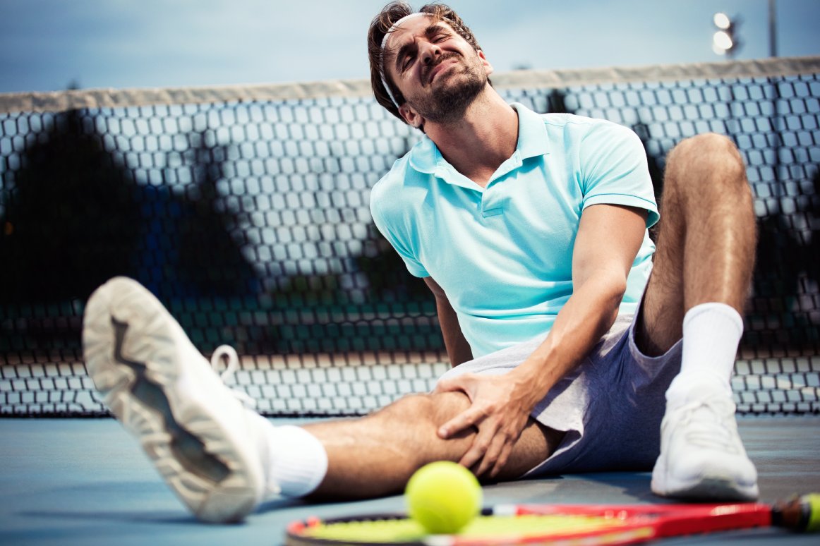 Blessure sportive.  Jeune joueur de tennis touchant son genou alors qu'il était assis sur le court de tennis