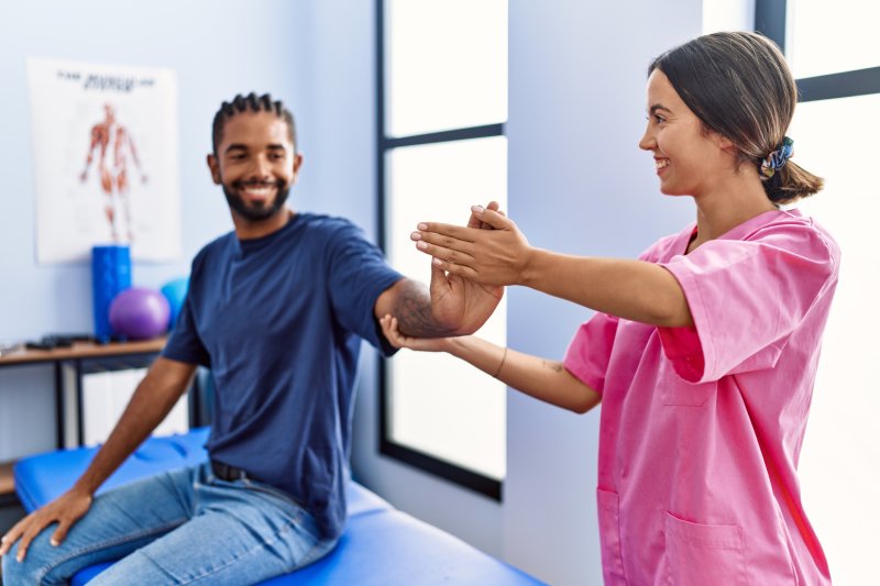 Homme et femme portant un uniforme de physiothérapeute ayant une séance de réadaptation qui s'étend du bras à la clinique de physiothérapie